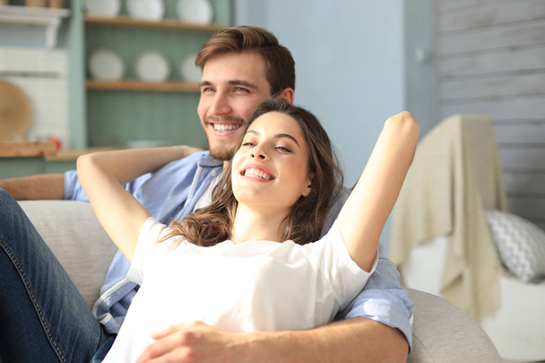 Portrait of cute young couple sitting in sofa. - Foto, Imagen