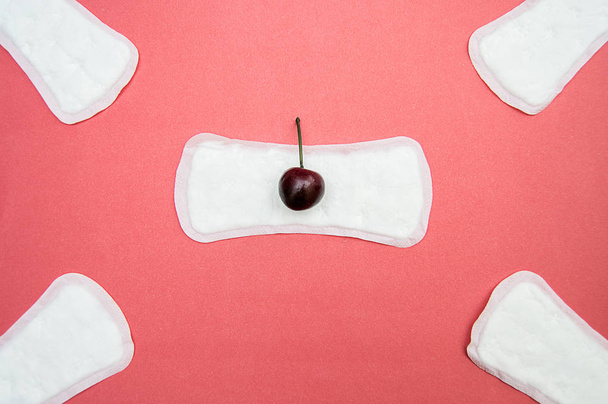 dámské hygienické podložky s třešní na pevném růžovém pozadí - Fotografie, Obrázek