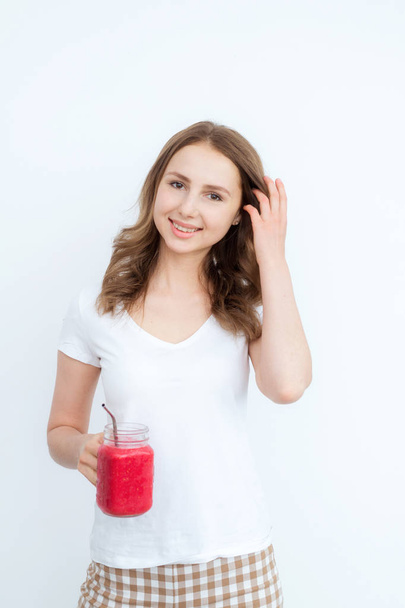 Berry fruit red smoothie in the hands of a young attractive girl on a white background. - Фото, зображення
