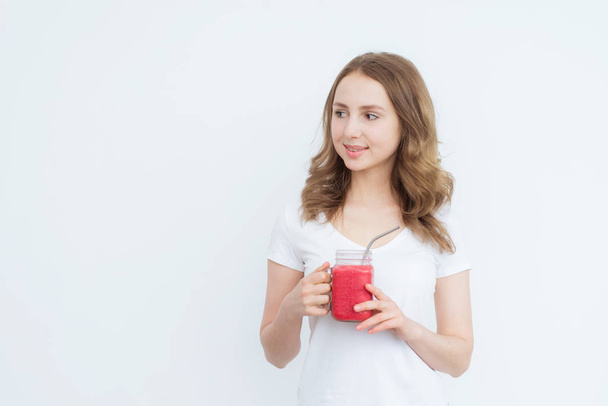 Berry fruit red smoothie in the hands of a young attractive girl on a white background. - Foto, Bild
