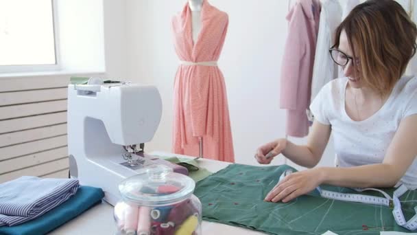Concepto de hobby y pequeña empresa. Joven diseñadora femenina diseña ropa en un brillante taller de estudio
 - Imágenes, Vídeo