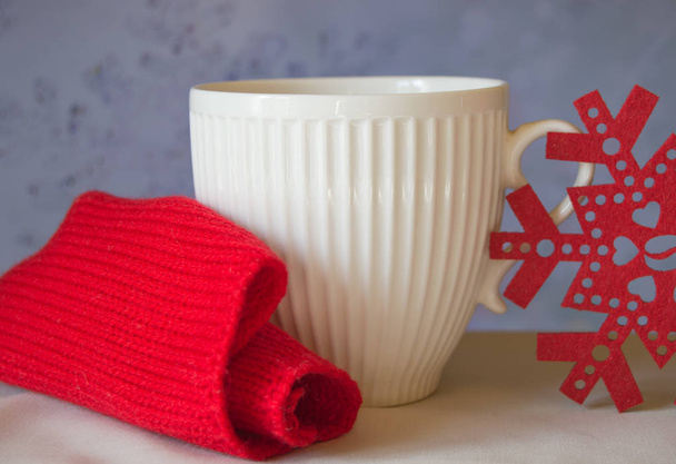 Kubek białych i śnieżynka z czerwonym szalikiem z dzianiny. Pojęcie Boże Narodzenie - Zdjęcie, obraz