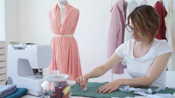 Concept van hobby en klein bedrijf. Jonge vrouwelijke ontwerper ontwerpt kleding in een lichte atelier workshop - Video