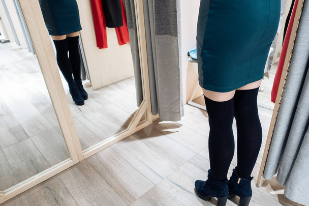 Young beautiful girl trying on new green dress in the fitting room in boutique. - 写真・画像