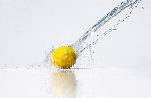 Water splash on yellow lemon on white background - Φωτογραφία, εικόνα