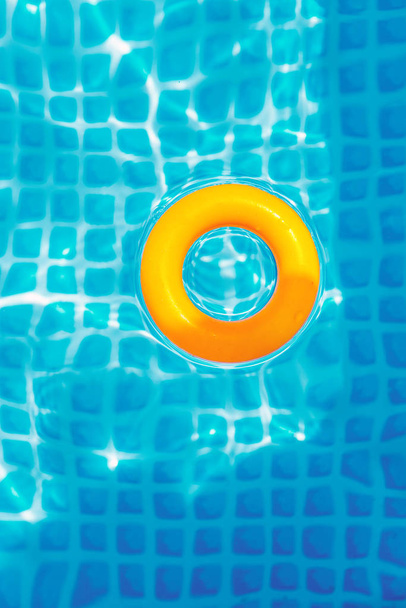 жовте надувне кільце, що плаває в басейні в сонячний день, вид зверху
 - Фото, зображення