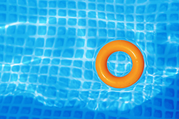 помаранчеве надувне кільце, що плаває в басейні в сонячний день, вид зверху
 - Фото, зображення
