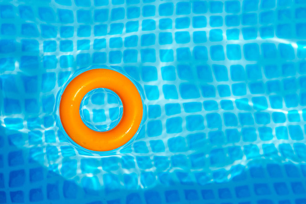 oranssi Puhallettava rengas kelluva uima-altaassa aurinkoisena päivänä, ylhäältä
 - Valokuva, kuva