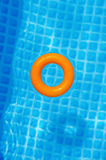 помаранчеве надувне кільце, що плаває в басейні в сонячний день, вид зверху
 - Фото, зображення