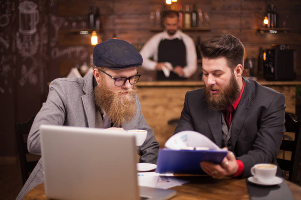 Aantrekkelijke zakenlieden die over financiën praten tijdens hun ontmoeting in een koffiezet Shop - Foto, afbeelding