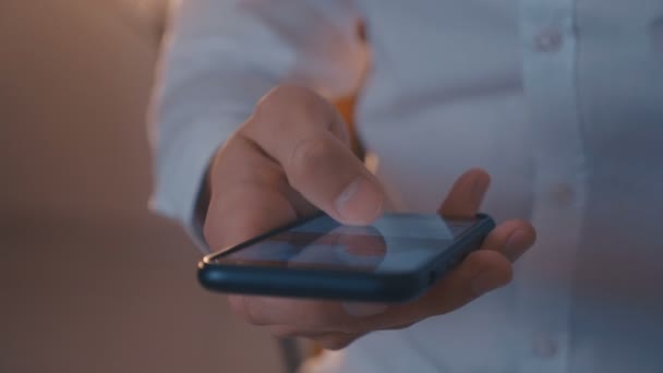 Чоловіча рука прокручує лінію новин на великому чорному смартфоні вночі
 - Кадри, відео