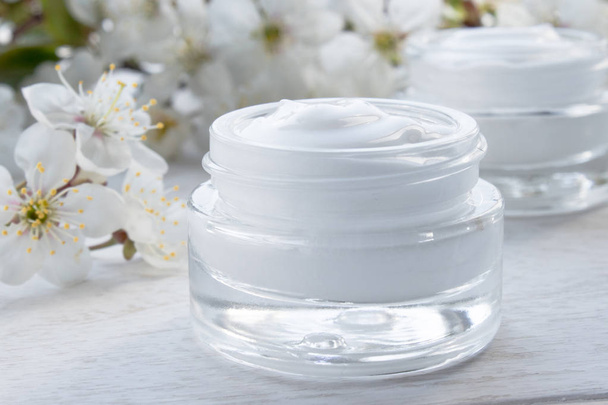 A jar of cream close-up, face cream surrounded by cherry flowers. - Foto, imagen