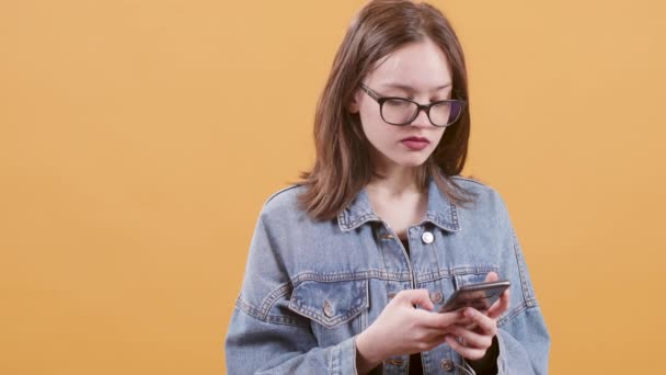 Cute teenage girl texting on her smartphone and seems impatient - Footage, Video