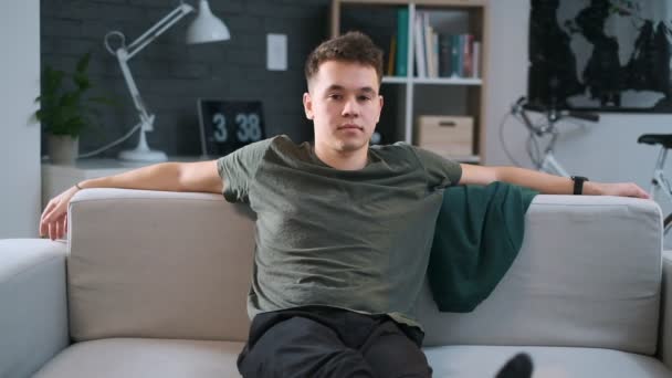 A teenage boy is resting on a couch with his legs streightened. - Záběry, video