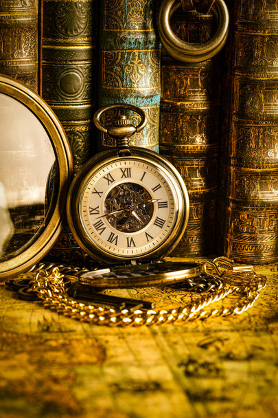 Antique clock on the background of a magnifying glass and books. - Fotografie, Obrázek