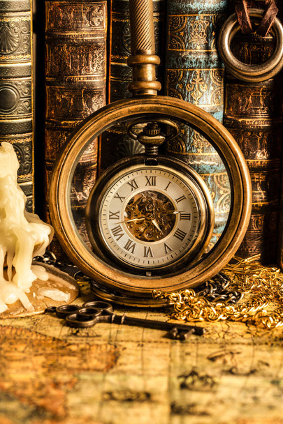 Antique clock on the background of a magnifying glass and books. - Fotó, kép