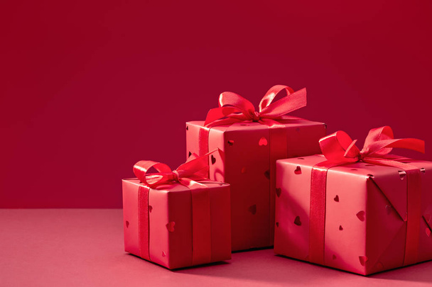 Stylish boxes with gifts in red paper with hearts, decorated with red satin ribbon with bows. Copy space. - Foto, imagen