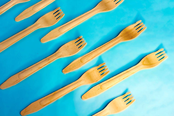 Disposable ecological wooden bamboo fork  pattern on light blue background. Environment friendly flat lay with free copy space for text. Selective background - Foto, Imagem