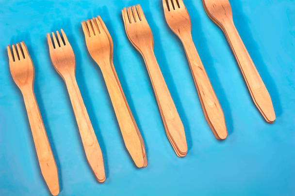 Disposable ecological wooden bamboo fork  pattern on light blue background. Environment friendly flat lay with free copy space for text. Selective background - Photo, Image