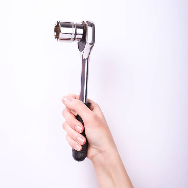 Ratchet wrench in a hand of the girl. Symbol of hard work, feminism and labor day. Isolate on white background. - Фото, изображение