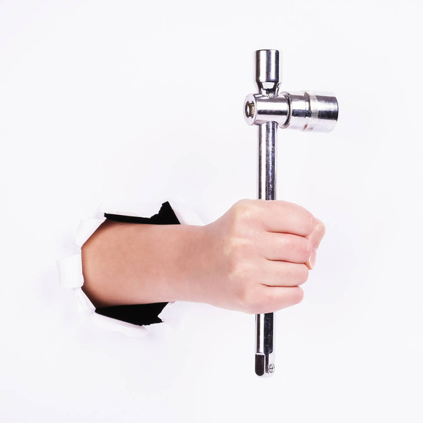 Stacked wrench in the hand of a girl. Symbol of hard work, feminism and labor day. Isolate on white background. - Fotó, kép