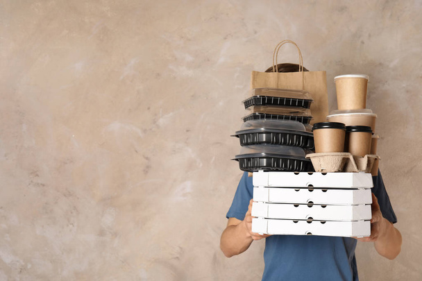 Courier with stack of orders on beige background, space for text. Food delivery service - Foto, immagini
