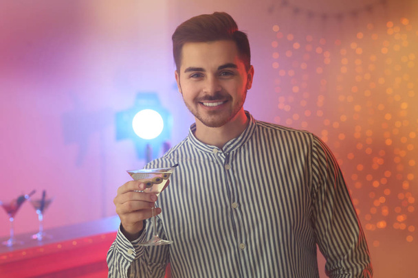 Partide elinde bir bardak martini kokteyli olan genç adam. - Fotoğraf, Görsel
