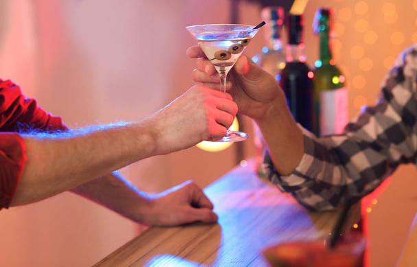 Young man taking martini cocktail from barman in pub, closeup - Fotó, kép
