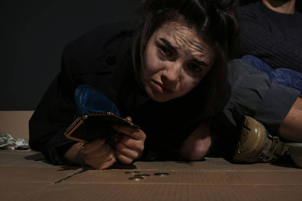 Poor woman with empty wallet and coins indoors - Foto, Imagen