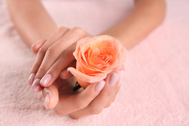 Closeup view of beautiful female hands with rose on towel, space for text. Spa treatment - 写真・画像