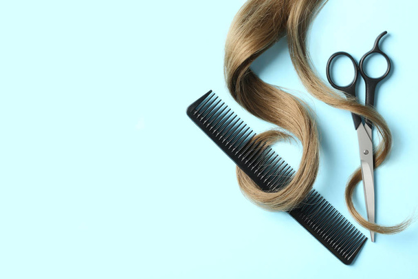 Flat lay composition with light brown hair, comb, scissors and space for text on color background. Hairdresser service - Zdjęcie, obraz