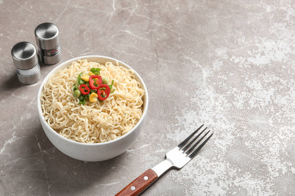 Bowl of noodles with vegetables and fork served on table. Space for text - Foto, Imagen