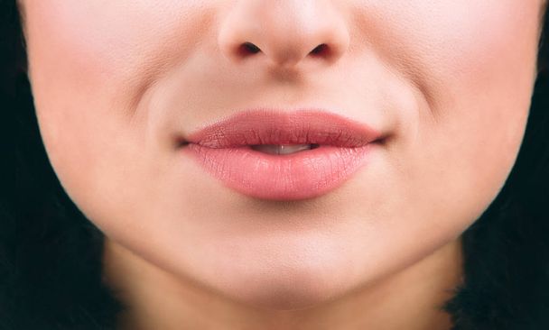 Gros plan de jolies lèvres de jeunes femmes souriant un peu. Cheveux noirs courts. Une peau saine. Vue coupée
. - Photo, image