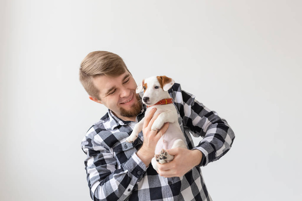 ανθρώπους, τα κατοικίδια ζώα και τα σκυλιά έννοια - νεαρός αγκαλιάζει αστεία κουτάβι σε λευκό φόντο - Φωτογραφία, εικόνα