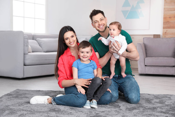 Happy parents and their cute children sitting on floor at home. Family time - Foto, Bild