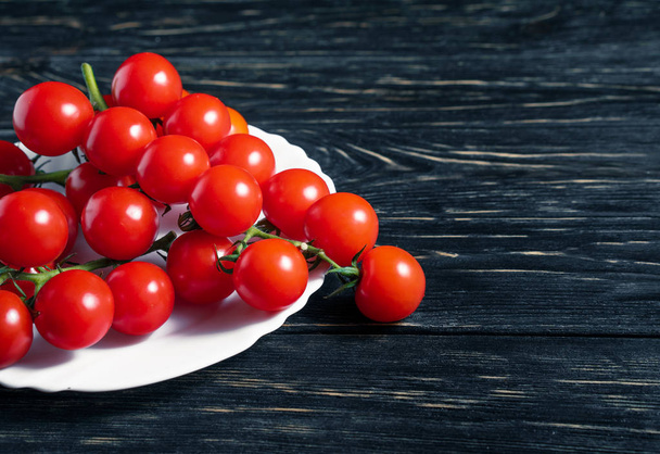 Cherry tomatoes in the white plate on the wooden table - Foto, imagen