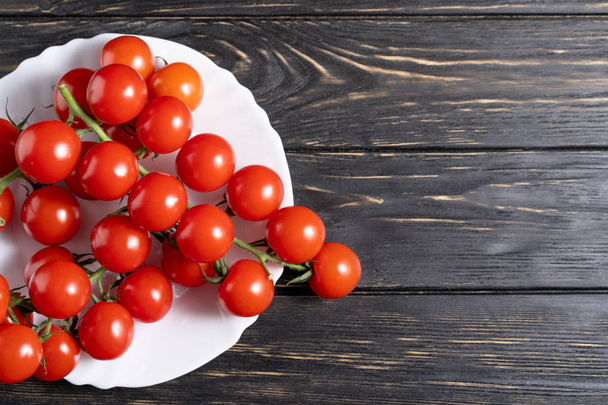 Cherry tomatoes in the white plate on the wooden table - Foto, Bild