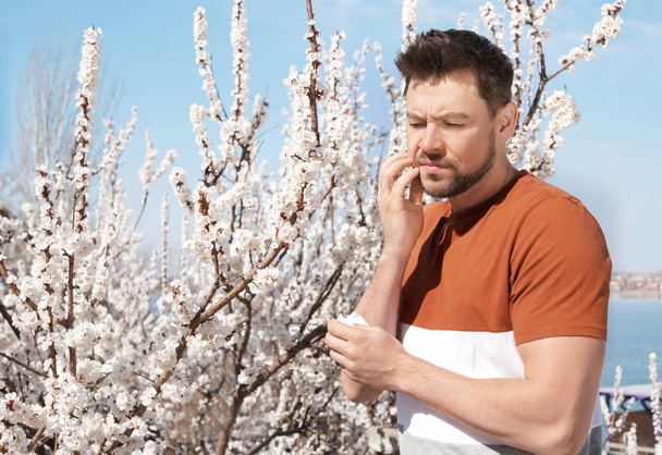 Man suffering from seasonal allergy outdoors, space for text - Valokuva, kuva