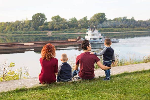 親として、子供の頃、自然のコンセプト - 緑の地面の上に座って、小さなボートを見て家族 - 写真・画像