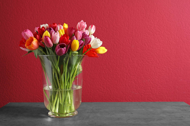 Vase with beautiful spring tulip flowers on color background. Space for text - Photo, Image