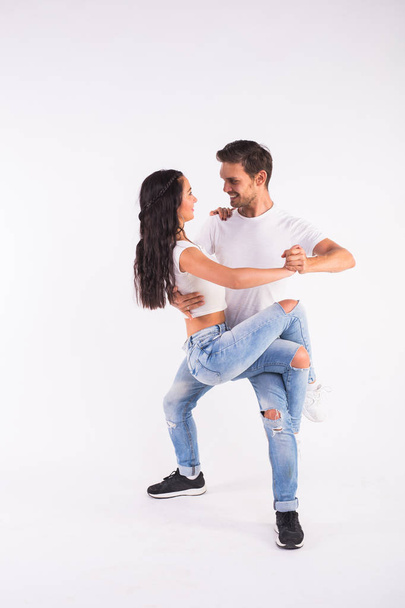 Νεαρό ζευγάρι χορό κοινωνικού χορού bachata, merengue, salsa, kizomba. Δύο κομψότητα πόζα στο λευκό δωμάτιο. - Φωτογραφία, εικόνα