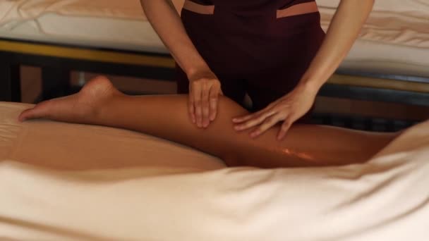 Masseur doing legs massage with oil to young woman in resort spa salon. Young woman receiving body massage in luxury spa center. Body relaxation and skin care. - Materiaali, video