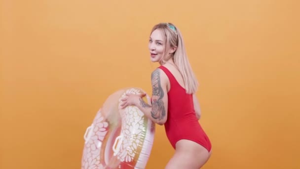 Sexy blonde vrouw in één stuk badpak spelen met een zwemmen ring - Video