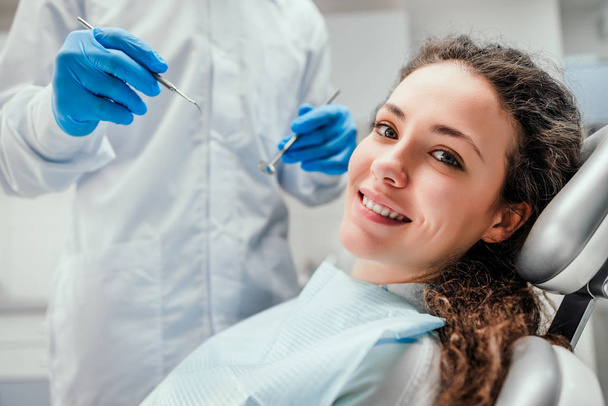 Smiling young woman receiving dental checkup. close up view. Healthcare and medicine concept. - Fotó, kép