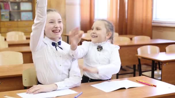 Schoolgirl raises her hand to answer the teacher's question.Two girls of  teenager schoolgirl are sitting at the table, one student raises her hand to answer the teacher's question, the second girl knows the subject of the lesson lesson. - Footage, Video