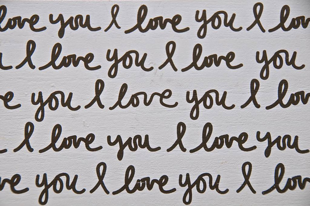 Doorlopende zwarte cursief afdrukken van de woorden "I Love You" op een blok hout - Foto, afbeelding