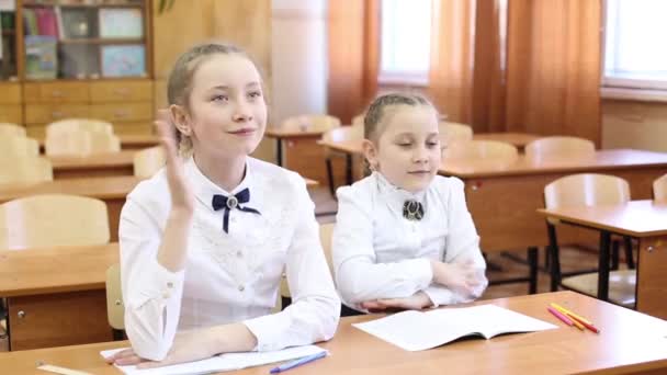 Schoolgirl raises her hand to answer the teacher's question.Two girls of a teenager schoolgirl are sitting at the table, one student raises her hand to answer the teacher's question, the second girl knows the subject of the lesson lesson. - Footage, Video