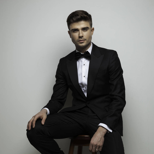 attractive man in black tuxedo standing on chair - Photo, Image
