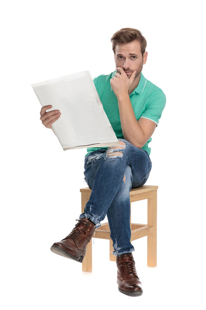 сидящий обеспокоенный парень читает плохие новости с рукой на подбородке
 - Фото, изображение