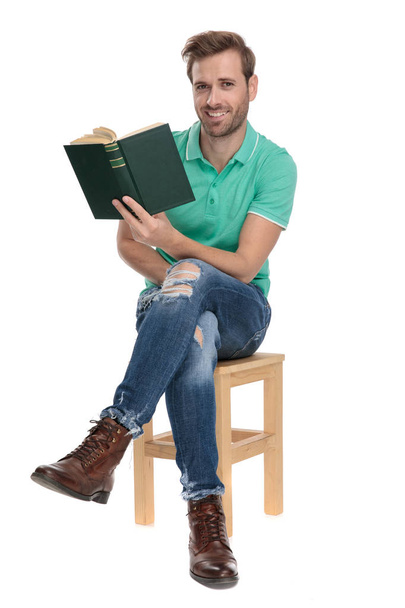 сидящий счастливый человек с книгой в руке со скрещенными ногами
 - Фото, изображение